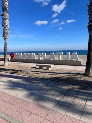 a sign for the beach with the ocean in the background at Apartamento bahía in Miami Platja