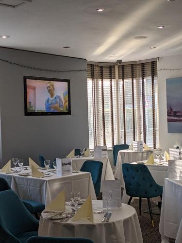 a dining room with white tables and chairs and a tv at Plough Hotel in Northampton