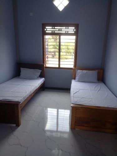 two beds in a room with a window at Billiards villa in Trincomalee