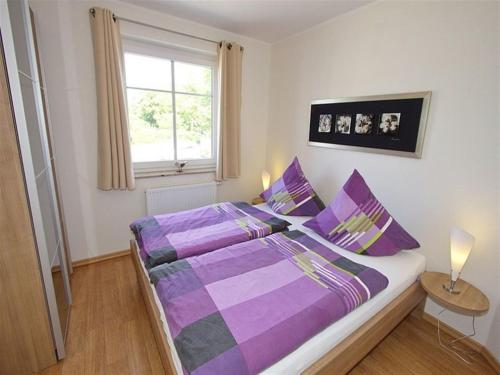 een slaapkamer met een bed met paarse lakens en een raam bij Ferienwohnung Feelmeer in Rerik