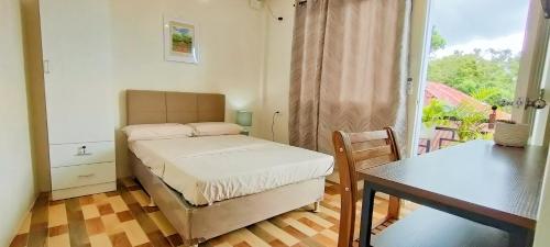 um pequeno quarto com uma cama e uma mesa em Intoy's Place em Panglao