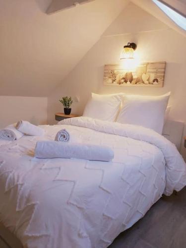 un lit blanc avec des draps et des oreillers blancs dans l'établissement Duplex Cosy 2, à Gouesnou