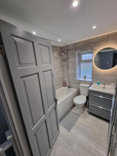 ein Badezimmer mit einer Tür, einer Badewanne und einem WC in der Unterkunft Dulverton house - 3 bed house /sleeps 6+ driveway+close to M1 in Nottingham