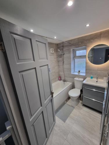 a bathroom with a door and a tub and a toilet at Dulverton house - 3 bed house /sleeps 6+ driveway+close to M1 in Nottingham