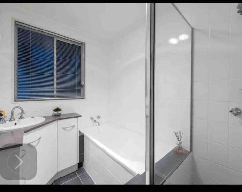 uma casa de banho branca com um chuveiro e um lavatório. em Resort style home pool spa sauna em Phillip