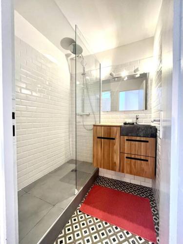 La salle de bains est pourvue d'une douche en verre et d'un tapis rouge. dans l'établissement Cosy T3 proche gare et Nansouty, à Bordeaux