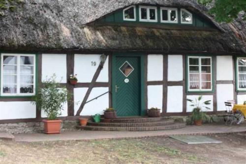 una casa con techo de paja y puerta verde en Landhaus Damerow 1, en Federow