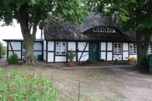 a white and black building with a thatch roof at Landhaus Damerow 2 in Federow