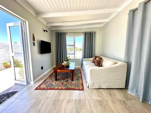 a living room with a white couch and a table at Brunia Bay Apartment in Hermanus