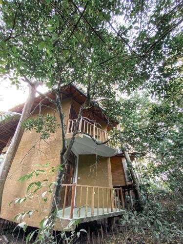 a building with a balcony in the middle of trees at Seasons Four Jungle Treehouse in Matara