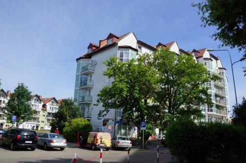 a large white building with cars parked in a parking lot at APARTAMENT NIEBO in Kołobrzeg