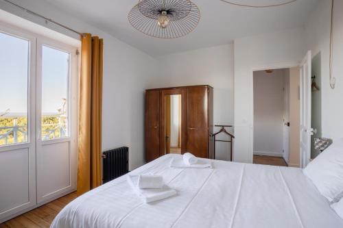 une chambre avec un grand lit blanc et une fenêtre dans l'établissement Les Beaux Étés, à Pléneuf-Val-André