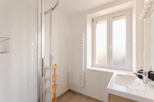 une salle de bain blanche avec un lavabo et une fenêtre dans l'établissement Les Beaux Étés, à Pléneuf-Val-André