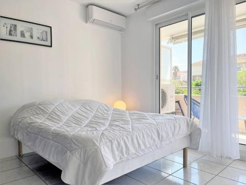 une chambre blanche avec un lit et une grande fenêtre dans l'établissement Appartement climatisé avec piscine, terrasse et parking - 6 couchages, près de la plage - FR-1-251-451, au Lavandou