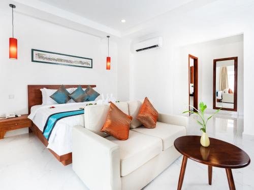 Le Kree Downtown Hotel في بنوم بنه: غرفة نوم بيضاء مع أريكة بيضاء وسرير