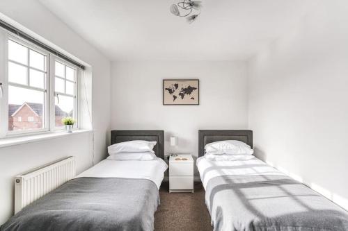 two beds in a room with white walls and windows at The Escape in Nottingham