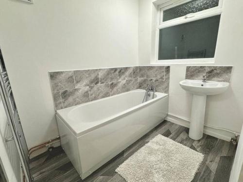 a white bathroom with a sink and a tub and a toilet at Spacious Accommodation for Contractors and Families 4 Bedrooms, Sleeps 8, Smart TV, Netflix, Parking, Only 20 Minutes to Birmingham, M6 J9 in Darlaston