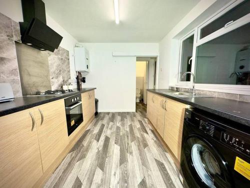 a kitchen with a washing machine in the middle of it at Spacious Accommodation for Contractors and Families 4 Bedrooms, Sleeps 8, Smart TV, Netflix, Parking, Only 20 Minutes to Birmingham, M6 J9 in Darlaston
