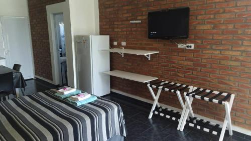 a room with a bed and a tv on a brick wall at Posada del Flamenco in Miramar