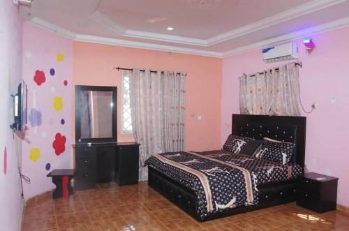 een slaapkamer met een bed in een kamer met roze muren bij Asoro Apartments in Benin City