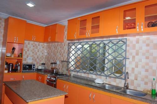 een keuken met oranje kasten en een wastafel bij Asoro Apartments in Benin City