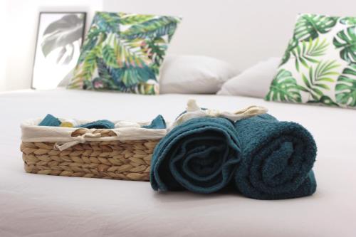 ein Korb mit Handtüchern auf einem Bett mit Kissen in der Unterkunft La Corte dei Creativi Comodo e Centrale in Mailand
