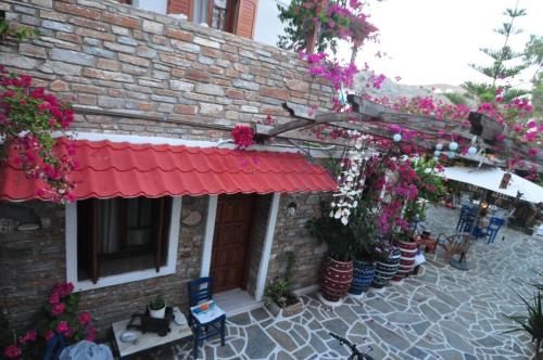 a brick building with a red awning and flowers at Zoe's Place in Ios Chora
