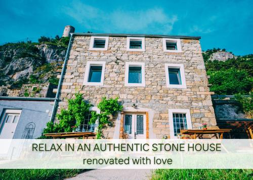 a stone house with a sign relax in an authentic stone house rewarded with love at Stone house with amazing view in Črni Kal