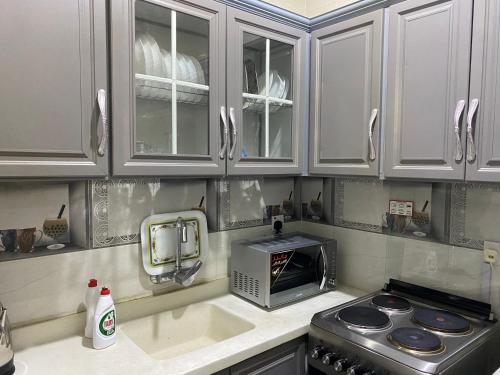een keuken met witte kasten en een magnetron bij شالية 3 غرف على شرم ابحر - جدة - السعودية in Obhor