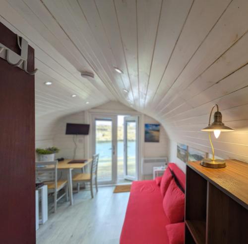 a living room with a red couch and a table at Glamping Pod for 2 Pod Beag Na Haun Eriskay in Eriskay