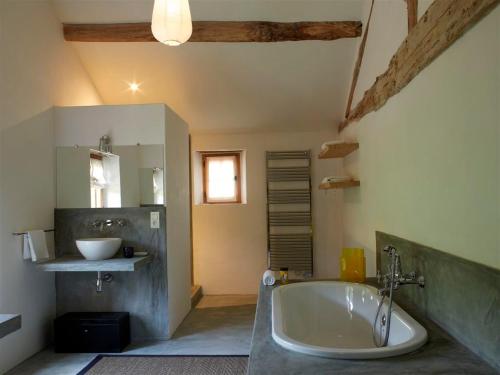 une grande salle de bain avec une baignoire et un lavabo dans l'établissement Le Pressoir - domaine du Chateau de La Bourlie - Boutique villa up to 12 guests, à Urval