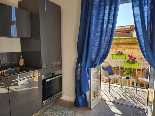 a kitchen with blue curtains and a view of a balcony at Delia in Sanremo