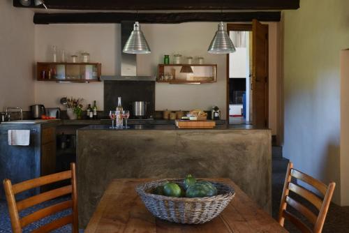 une cuisine avec une table avec un bol de fruits dessus dans l'établissement Le Pressoir - domaine du Chateau de La Bourlie - Boutique villa up to 12 guests, à Urval