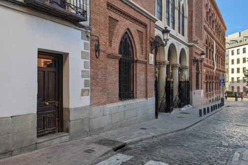 uma rua vazia com um edifício de tijolos e uma porta castanha em Madrid - La Latina de 1 a 4 alojados em Madrid