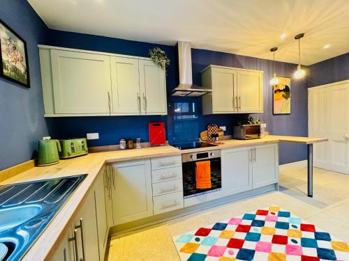 a kitchen with white cabinets and a blue wall at Merton Retreat - City Luxury, Free Parking, Central in Leicester