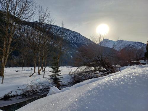 a snow covered field with the sun behind a mountain at Haus Kohler in Häselgehr