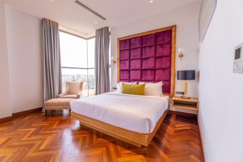 a bedroom with a large bed and a chair at Broadwalk Residency in Nairobi