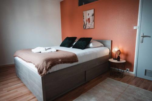 une chambre avec un grand lit aux murs orange dans l'établissement Le Cosmic Bliss • Chic Urbain au cœur du Berry, à Châteauroux