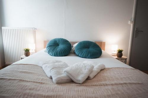 a bed with two blue pillows and towels on it at Le Cosmic Bliss • Chic Urbain au cœur du Berry in Châteauroux