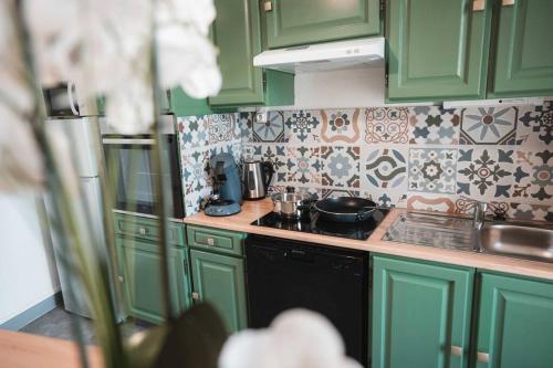 a kitchen with green cabinets and a stove top oven at Le Cosmic Bliss • Chic Urbain au cœur du Berry in Châteauroux