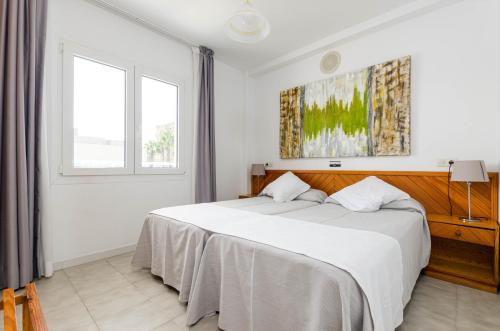 a bedroom with a large white bed in a room at Mar Brava Apartments in Can Picafort