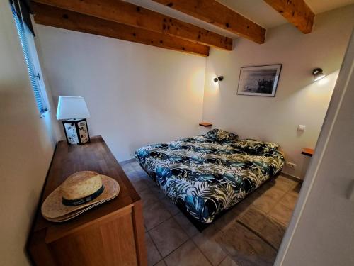 Le Côté Lub في بيرتويس: غرفة نوم صغيرة مع سرير وقبعة على طاولة