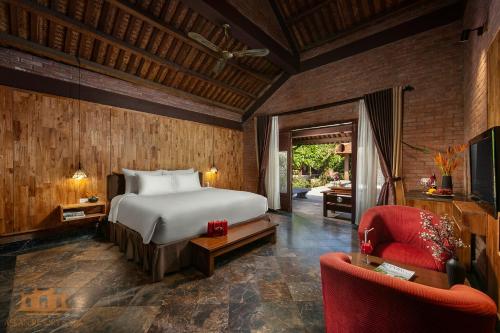 a bedroom with a bed and a red chair at Asean Resort - Shiki Onsen & Spa in Hanoi