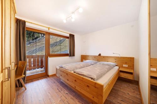 1 dormitorio con cama de madera y ventana en Unterdurachhof Apartment Martin, en Ultimo