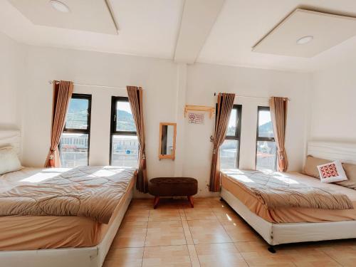2 camas en una habitación con ventanas en Tiga Mahkota homestay, en Diyeng