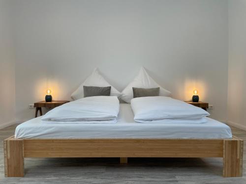 1 cama con sábanas y almohadas blancas y 2 lámparas en SPLENDID I Unique Spacious Apartment, en Hannover