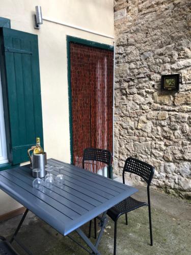 a blue picnic table with two chairs in front of a building at Cosy house in Casteljaloux