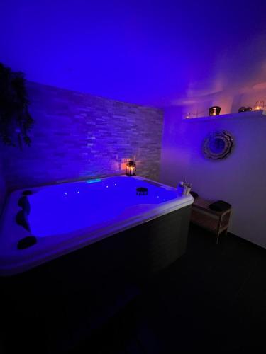 a bathroom with a large tub with a purple lighting at Villa Louméa - Le Chalet avec jacuzzi in Friesenheim