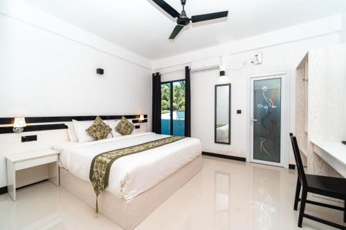 a white bedroom with a bed and a desk at The Shark Residence in Fuvahmulah