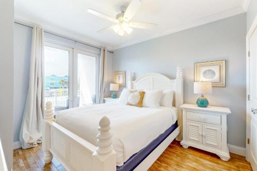 a white bedroom with a white bed and a window at Tranquil Harbour 102 in Mexico Beach